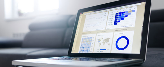 Laptop on a desk with statistic graphics on the screen.