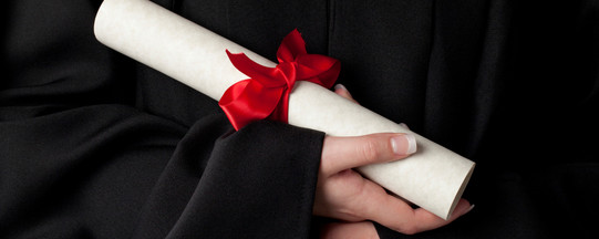 A rolled document with red bow is held by hands. 