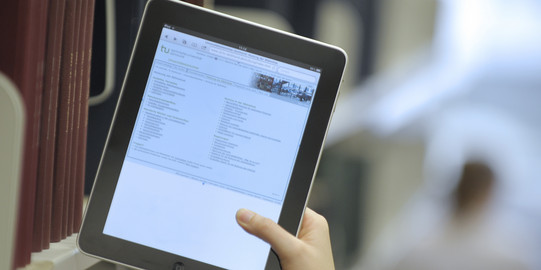 Photo of a tablet with the TU University Library home page open.